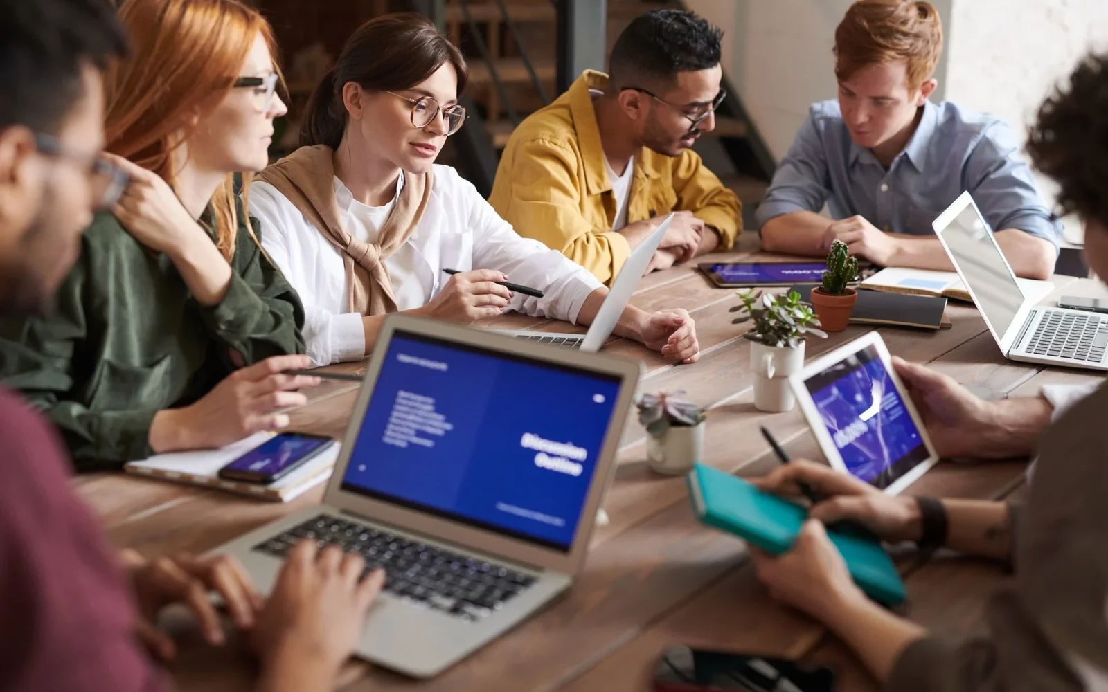 Office team comparing laptop information and written notes
