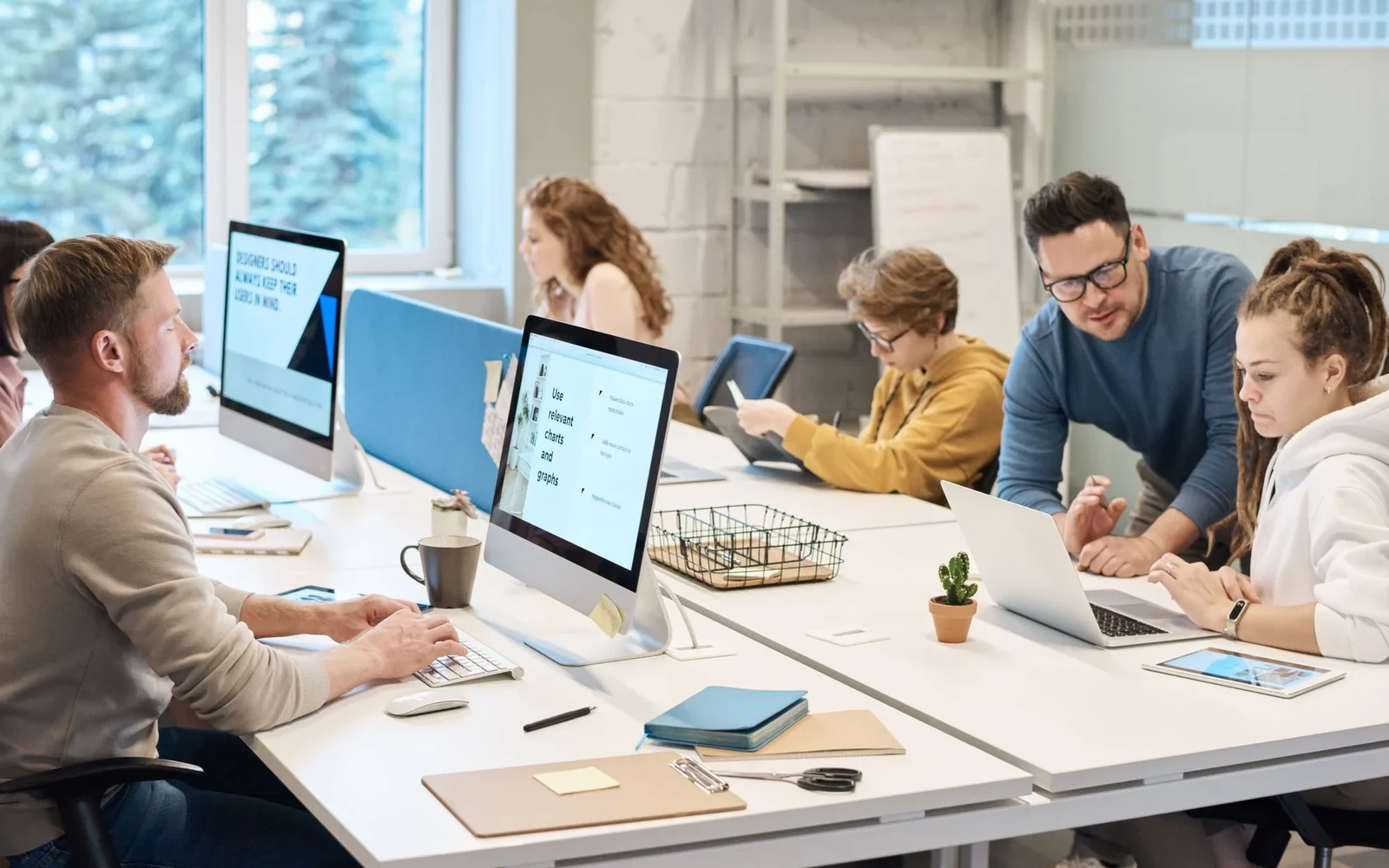 Colleagues working at computers around a shared office table
